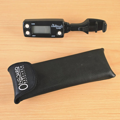 Top-down view of The Intellitouch Tuner and carrying pouch on a wooden surface.