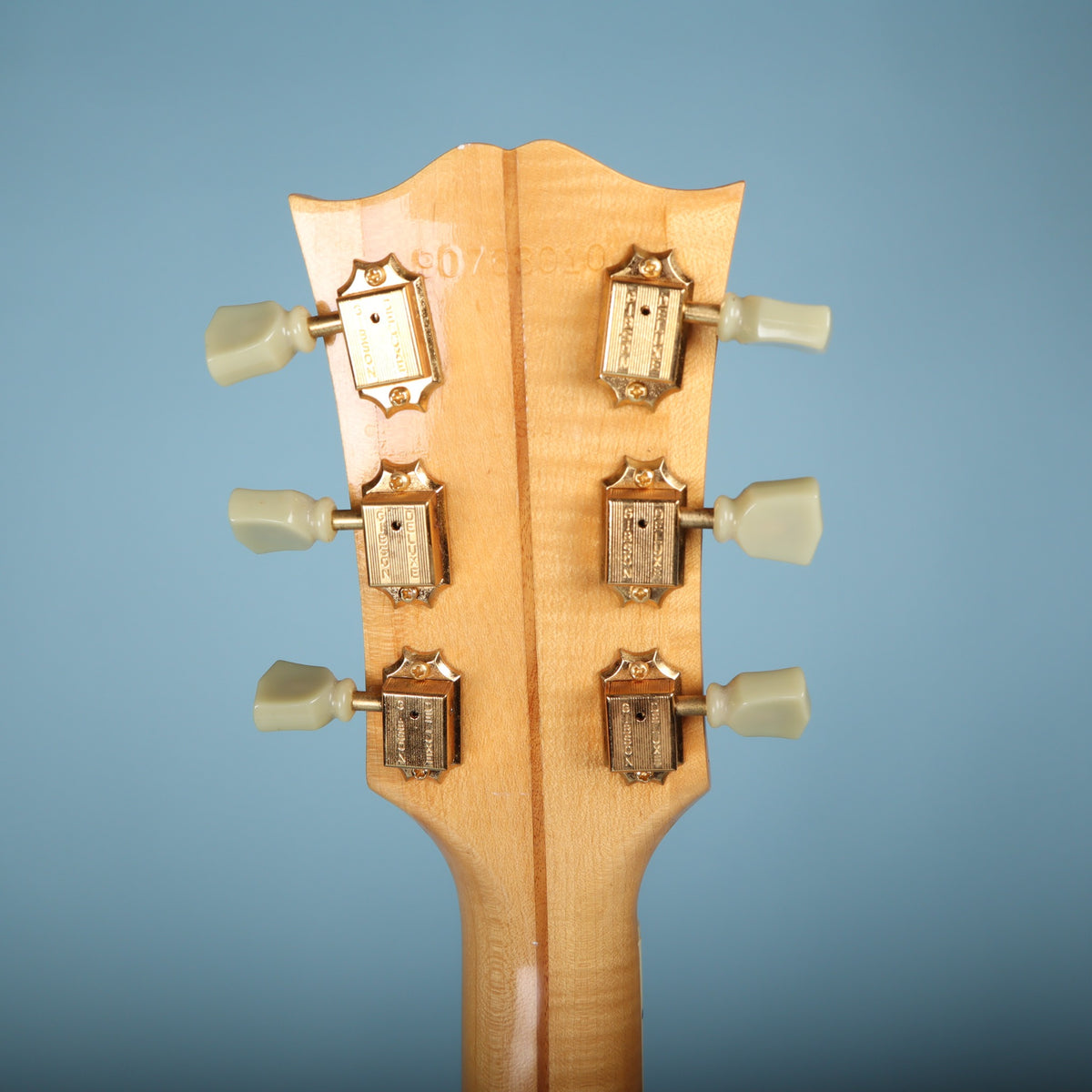 Back of headstock showing gold Gibson Deluxe tuners and stamped serial number 90763010.