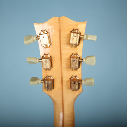 Back of headstock showing gold Gibson Deluxe tuners and stamped serial number 90763010.