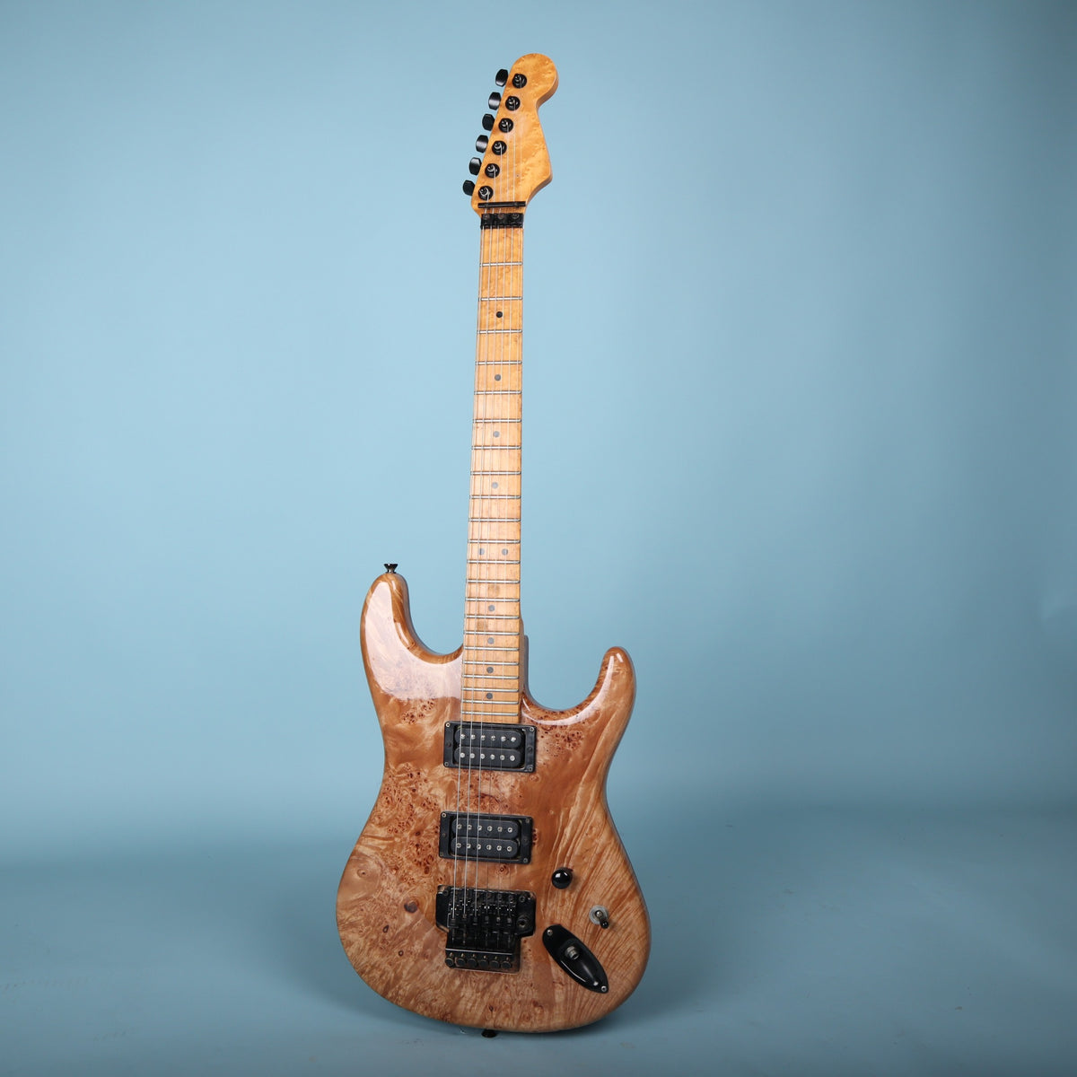 Full front view of 1980s Warmoth electric guitar against blue backdrop.