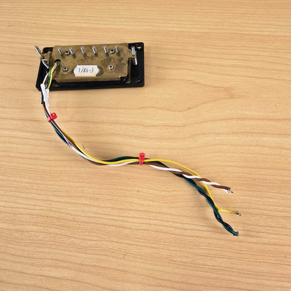 Underside of Schaller humbucker displaying brass plate, height screws, and multi-color lead wire
