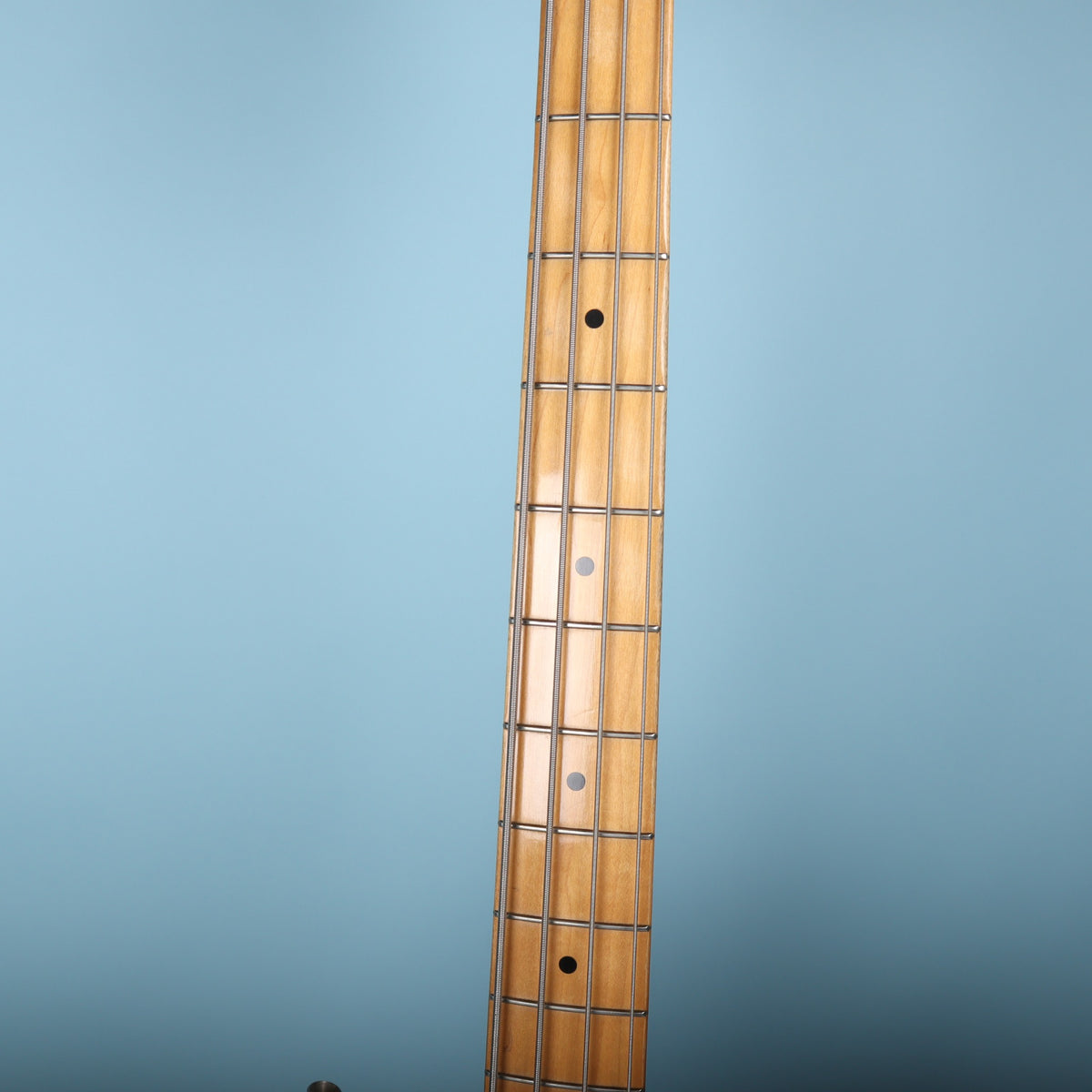 Close-up of the maple fretboard with black dot inlays on the Fender Precision Bass.