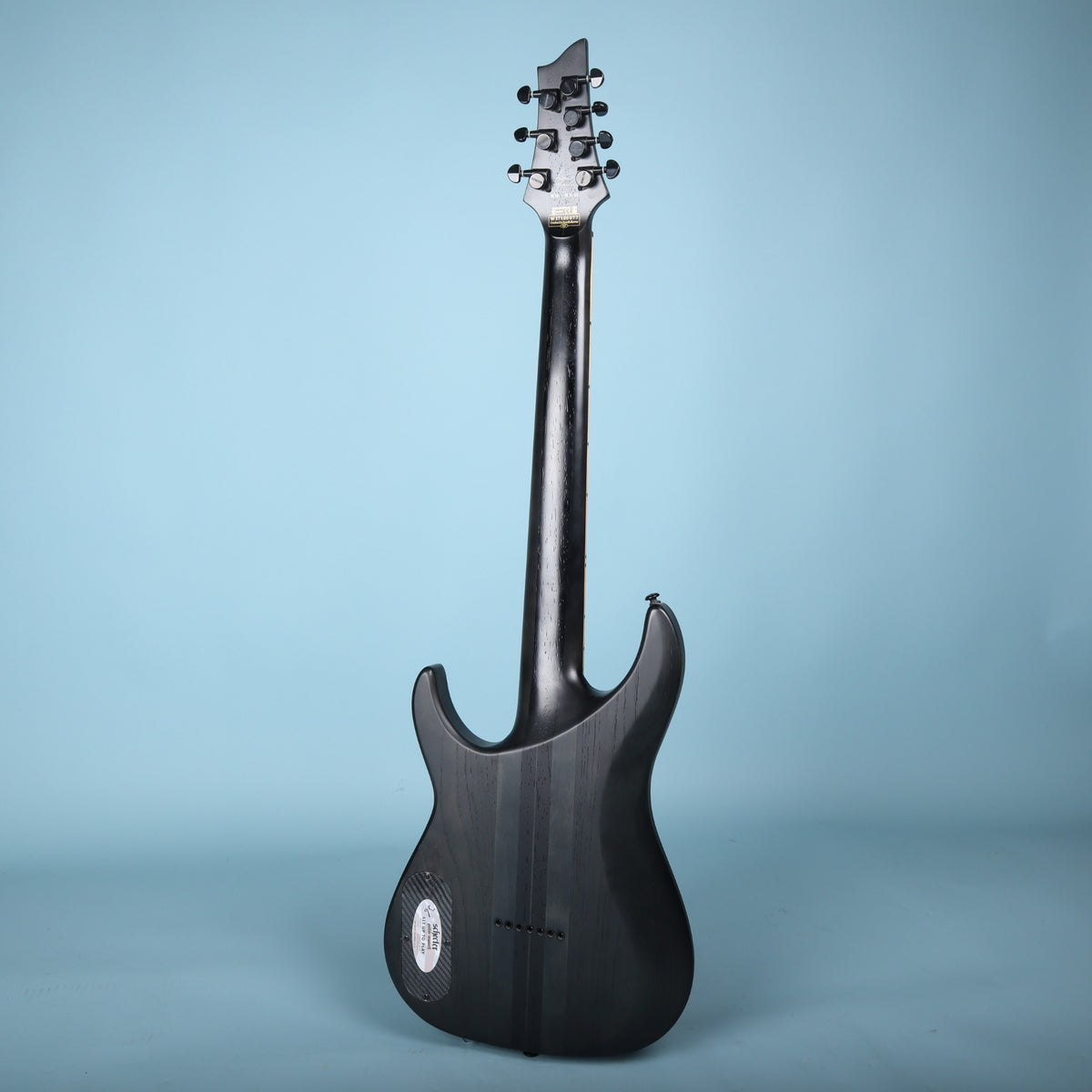 Full rear view of the Schecter KM-7 MK-II guitar against a blue backdrop