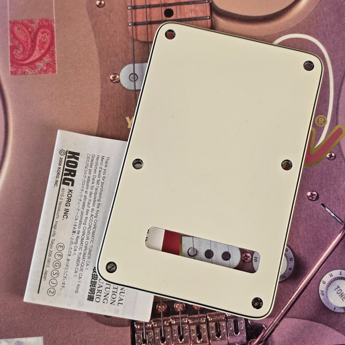 Fender Stratocaster off white tremolo cover next to Korg manual