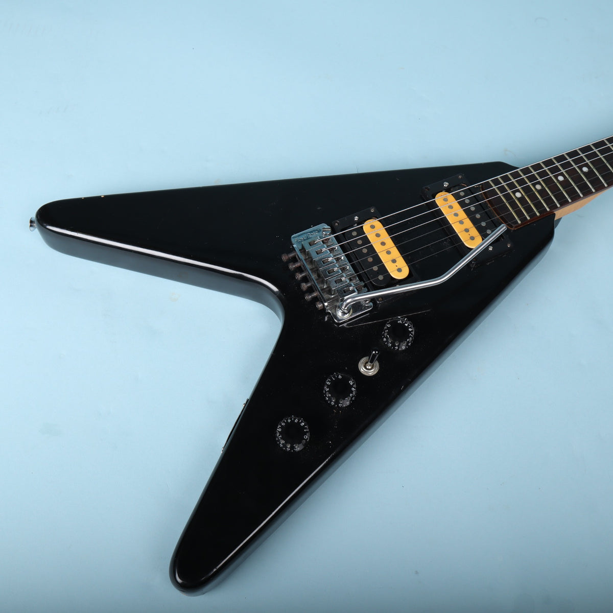Angled front view of the black body with tremolo arm and control knobs.