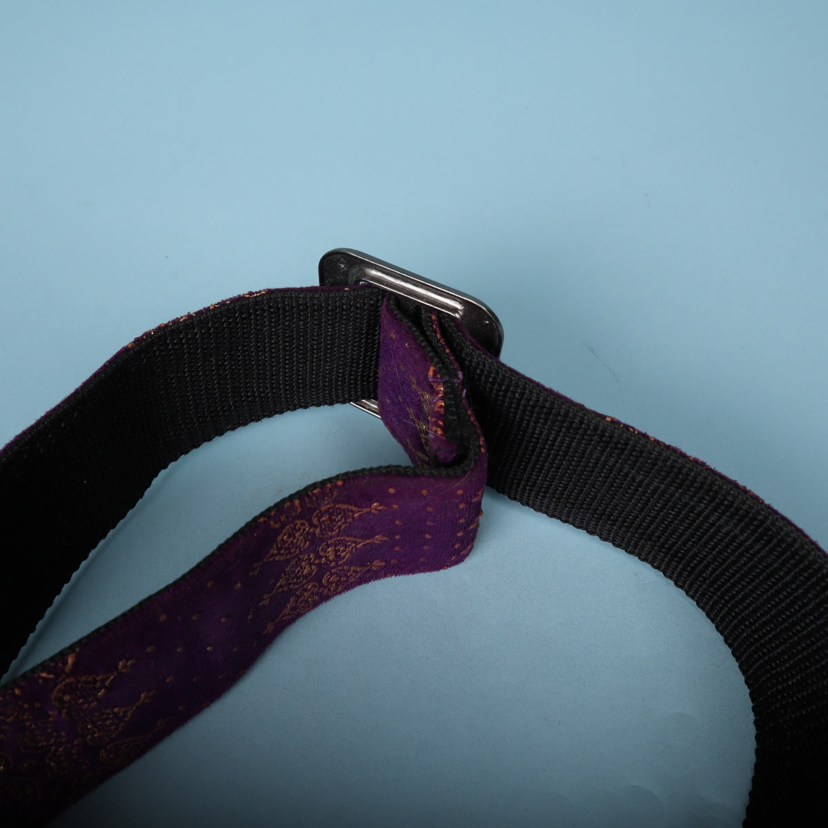 Detail view of the metal adjustment slide buckle on the black webbing