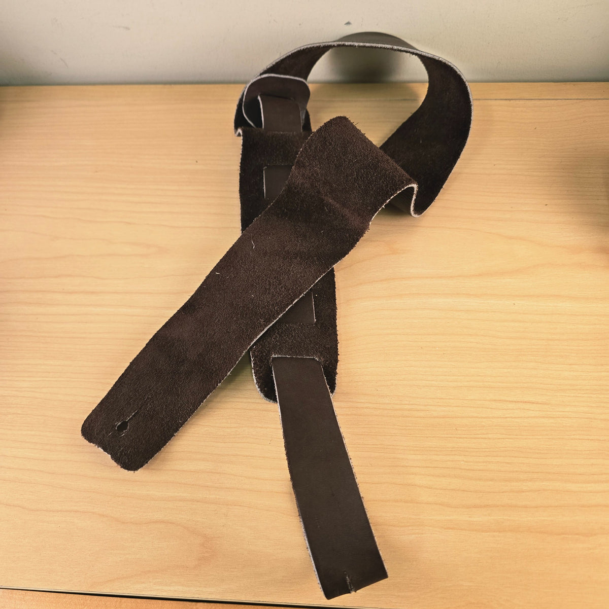 Underside of the Ernie Ball brown leather guitar strap showing the natural suede backing