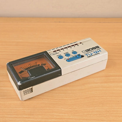 Angled top-front view of a Boss TU-12H Chromatic Tuner showing the analog meter and controls.