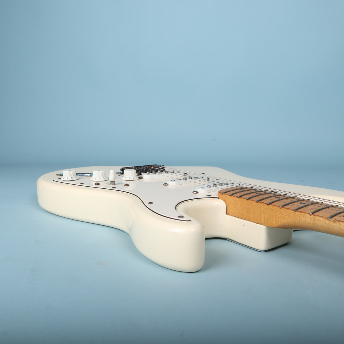 Side perspective of guitar body cutaways and maple neck joint