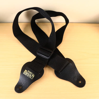 Full front view of black Fort Bryan webbing guitar strap with gold logo stamped on leather end.