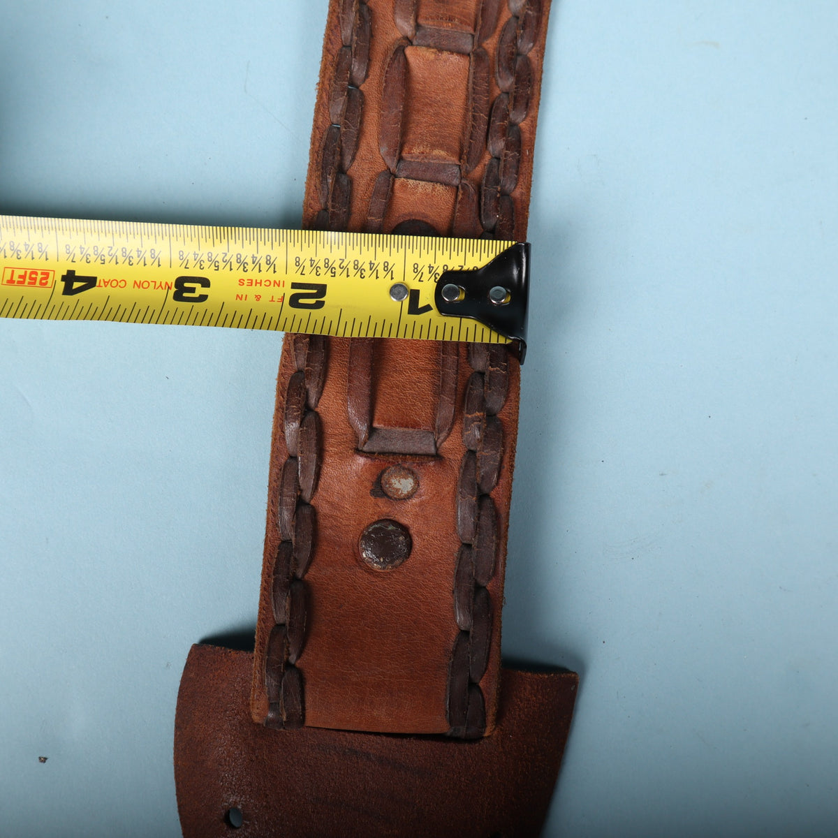 Vintage leather guitar strap width measured at 2 inches with tape measure