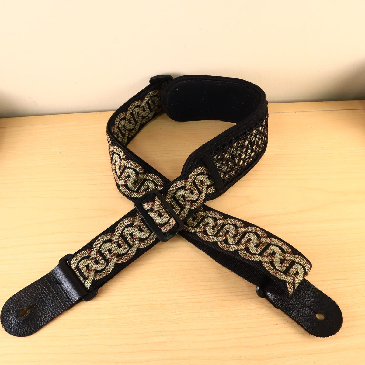 The Planet Waves Celtic pattern guitar strap laid out showing both leather end tabs.