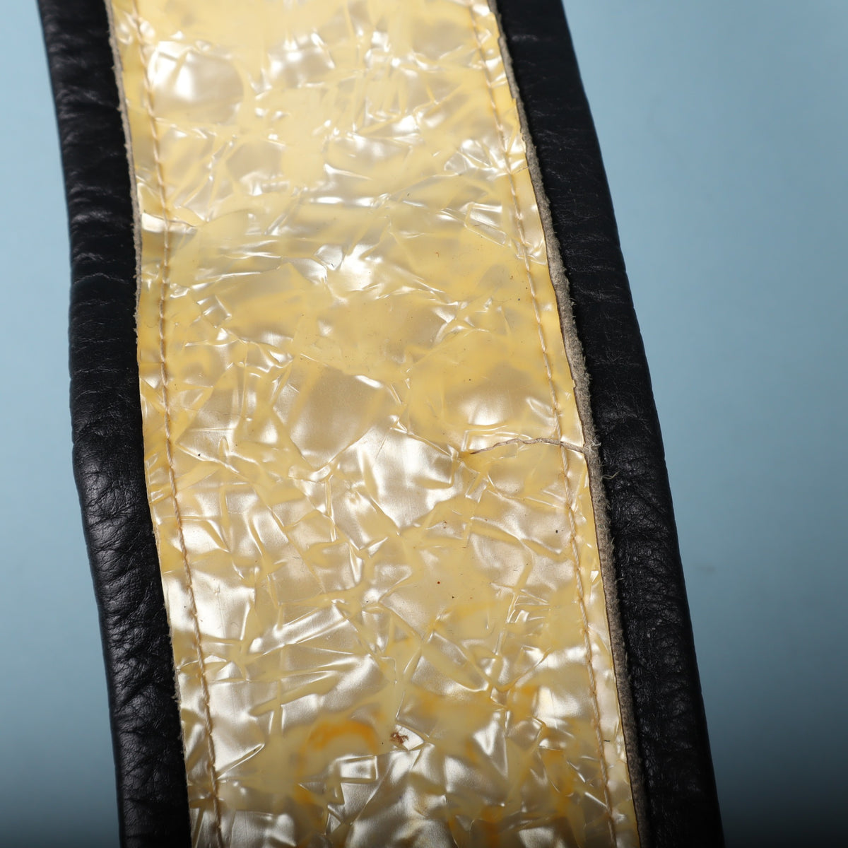 Macro shot highlighting the pearloid pattern and hairline finish cracks across the surface.