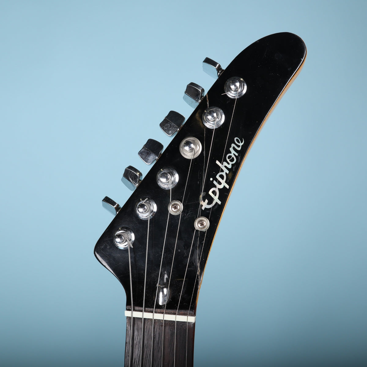 Pointed headstock front of the Epiphone V2 showing logo and bone nut.