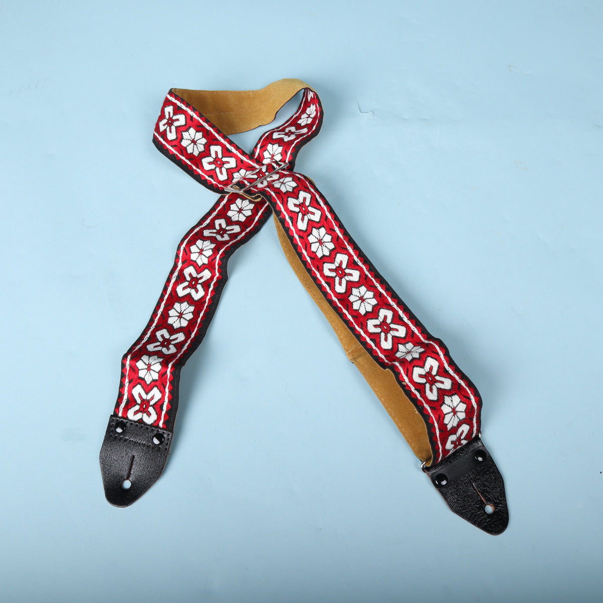 Front overview of the red and white floral woven guitar strap with metal adjustment buckle