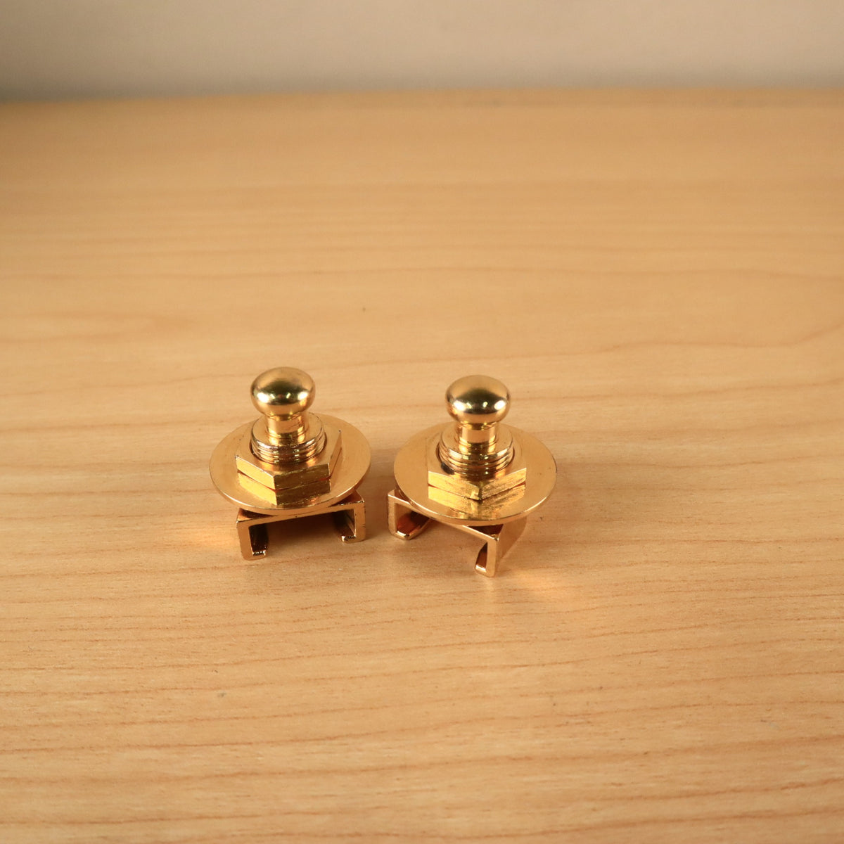Side angled view of two gold Schaller strap lock assemblies showing release knobs, nuts, and washers.