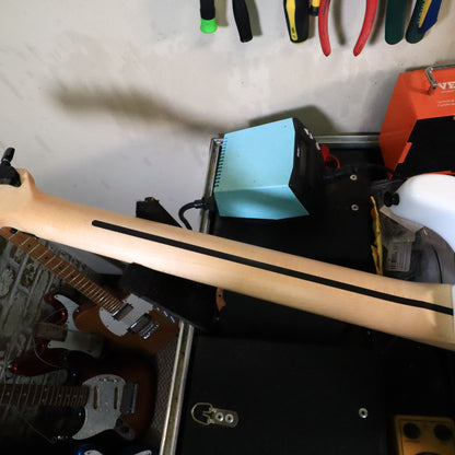 Bottom edge view of guitar body resting on padded tech workbench.