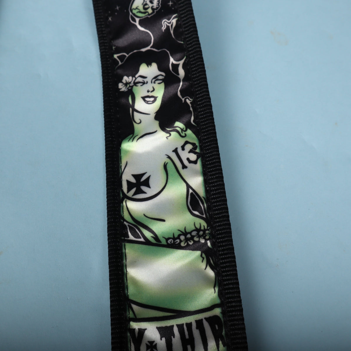 Close-up view highlighting the detailed tattoo-style pinup zombie illustration in toxic green.