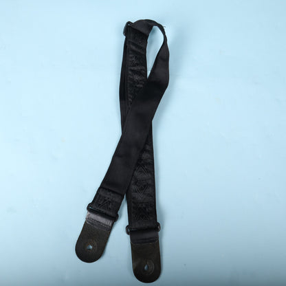 Underside of the Planet Waves woven guitar strap showing black backing webbing and leather tabs.