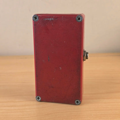 Bottom view showing the red metal backplate with corner screws and surface scratching.