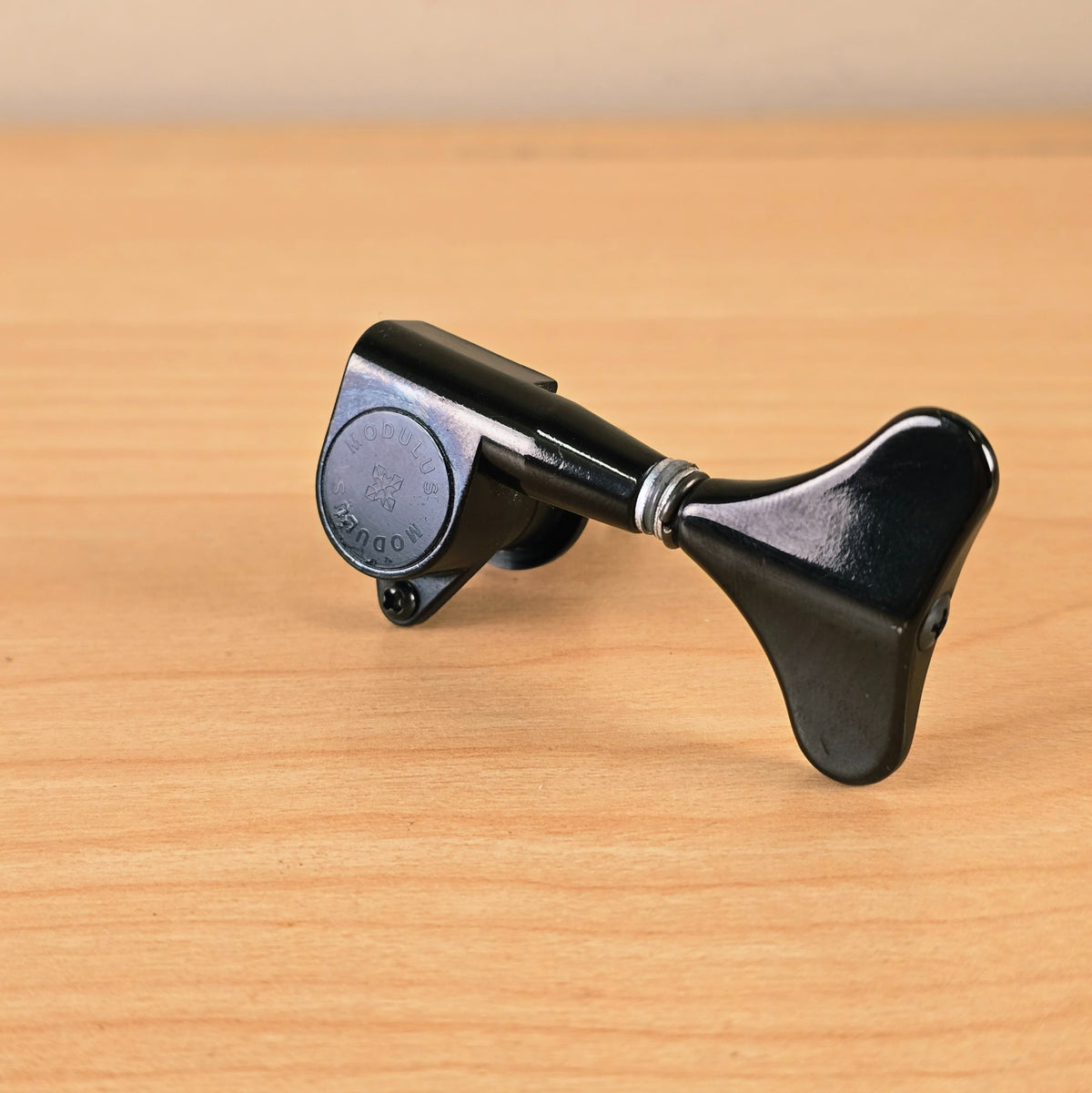Gotoh Modulus bass tuning peg in black viewed from the front angle on a wooden surface