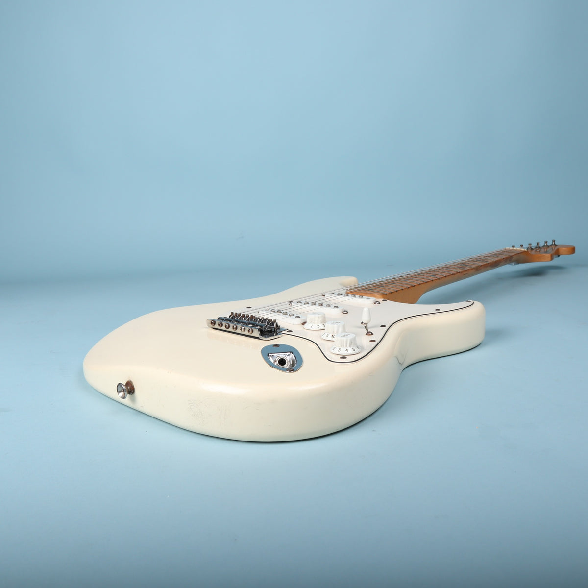 Low-angle perspective of guitar body edge and output jack plate