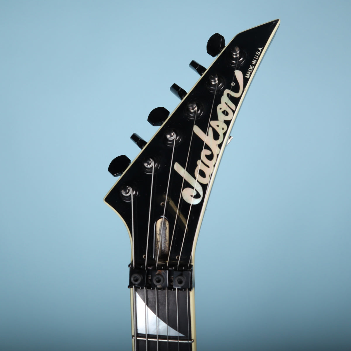 Front close-up of the Jackson headstock with locking nut and truss rod cavity