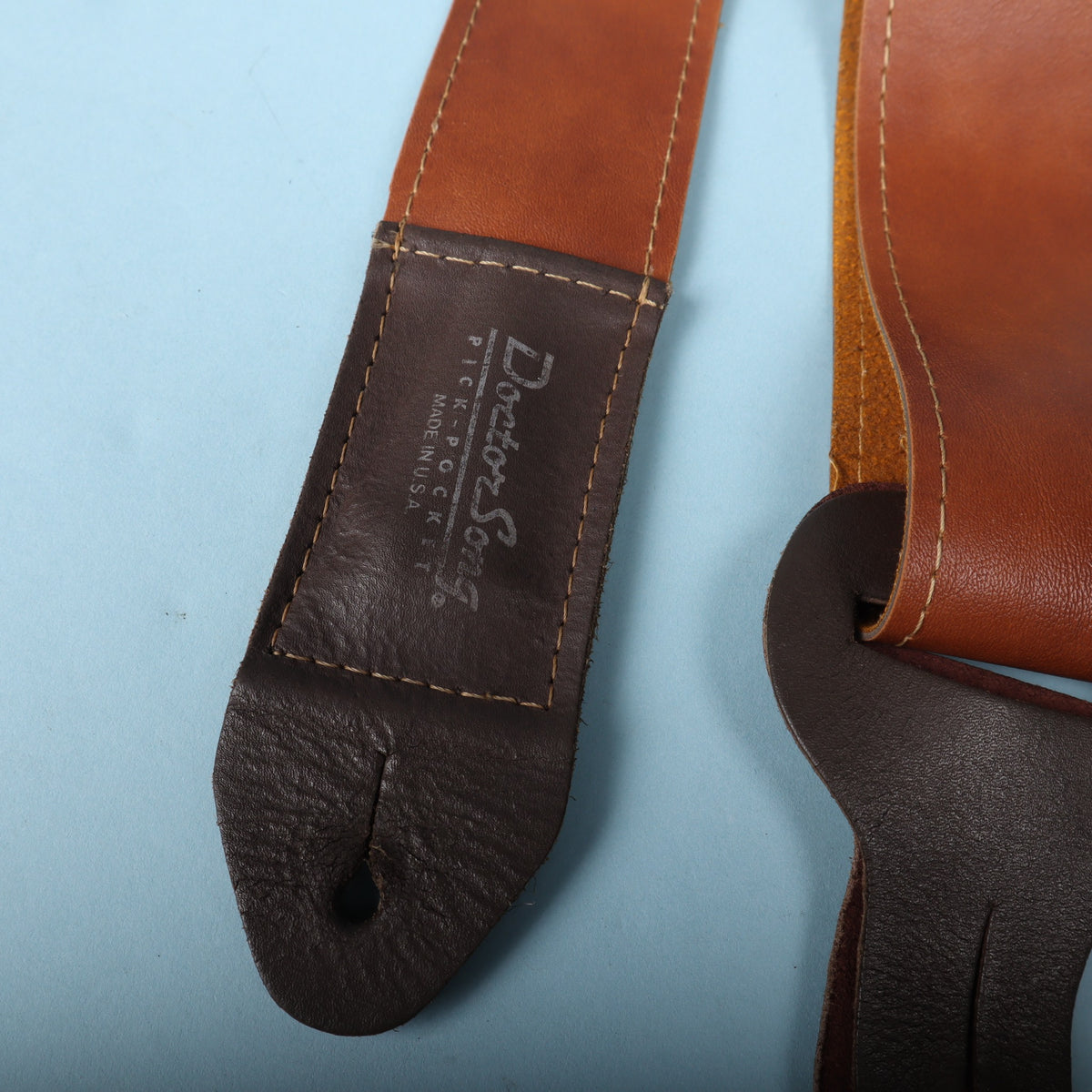 Close-up of the dark brown leather strap end stamped with Doctor Song Pick-Pocket Made in U.S.A.