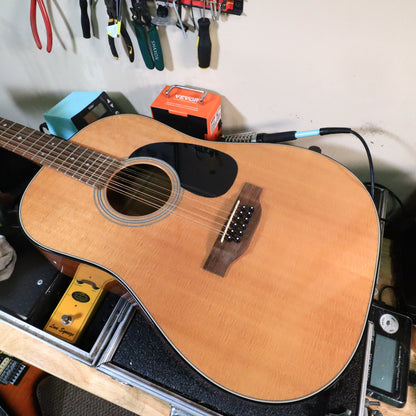 Guitar resting on bench highlighting soundhole and 12-string bridge