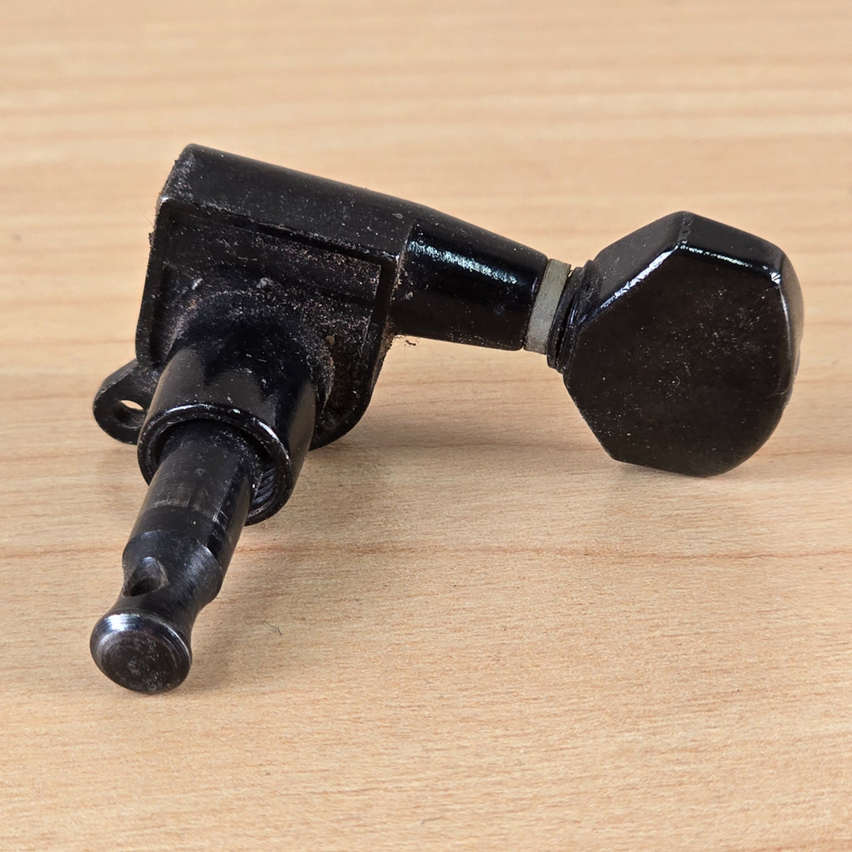 Underside view of the black Jackson guitar tuning machine showing the shaft and mounting screw tab.