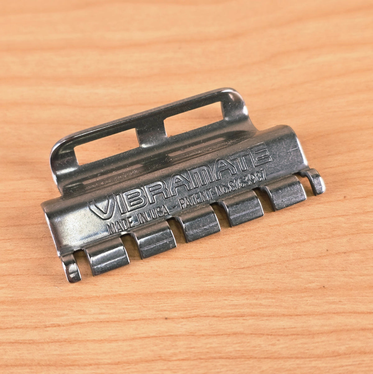 Angled top-down view of the Vibramate Spoiler on a wooden surface highlighting the metal finish.