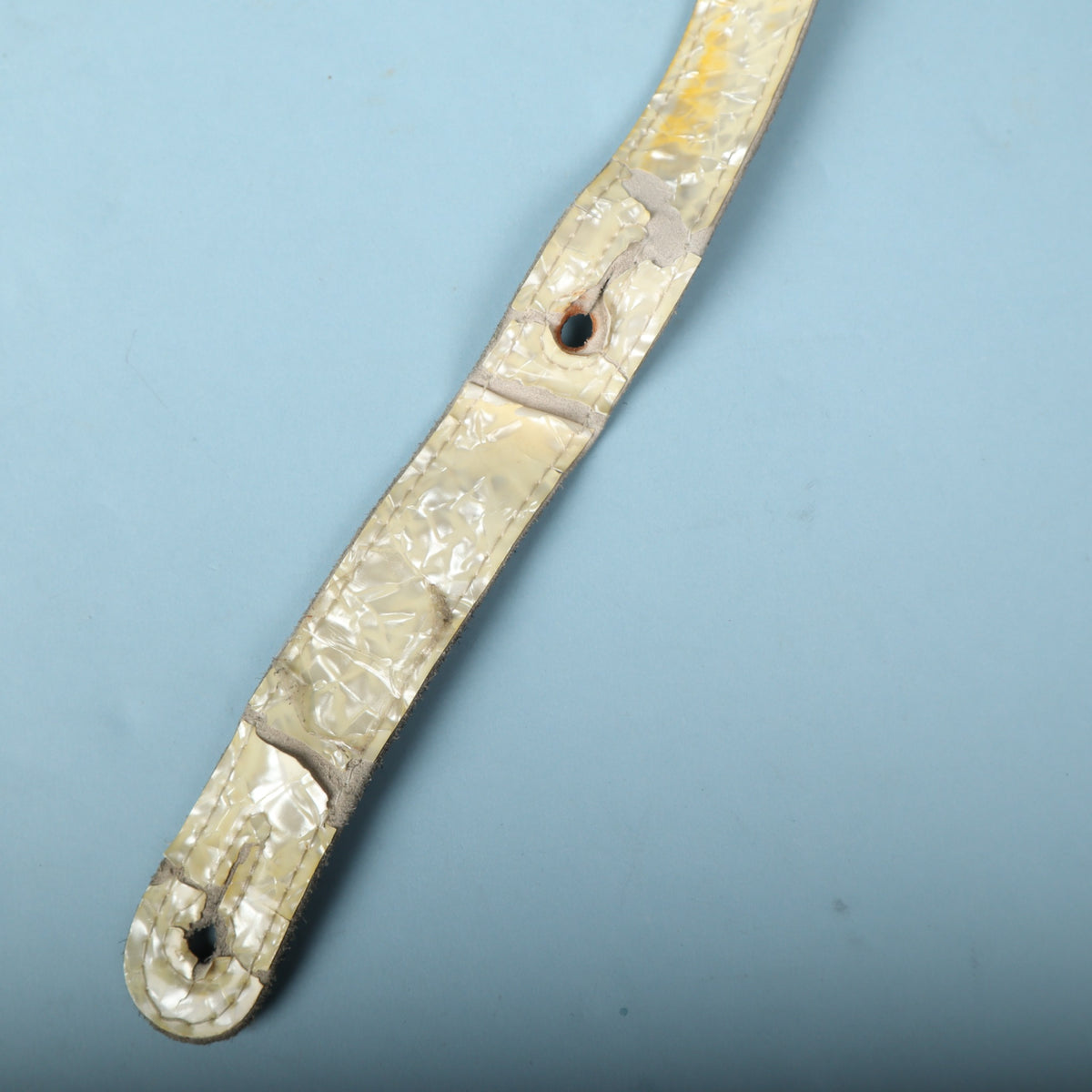 Close-up of the adjustment tail showing cracking and peeling on the pearloid surface.