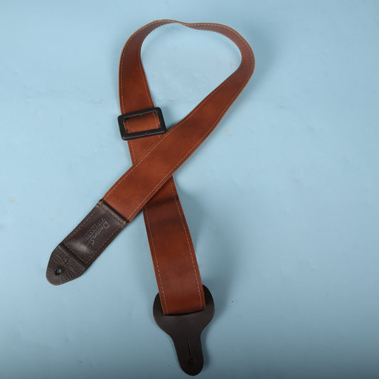 Doctor Song Pick-Pocket leather guitar strap laid out in a loop against a light blue background.