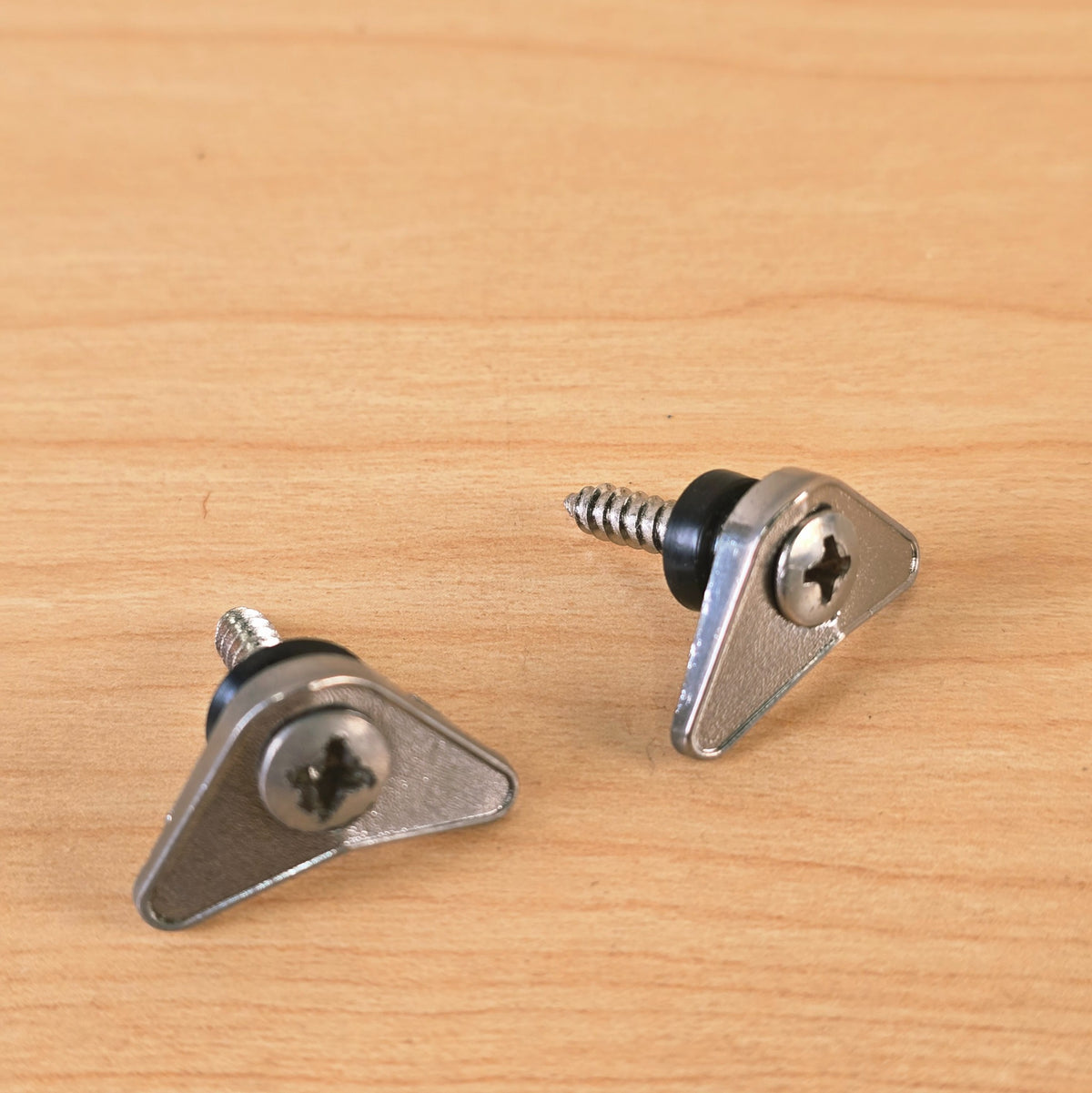 Top view of two chrome triangular string guides showing the Phillips mounting screws.