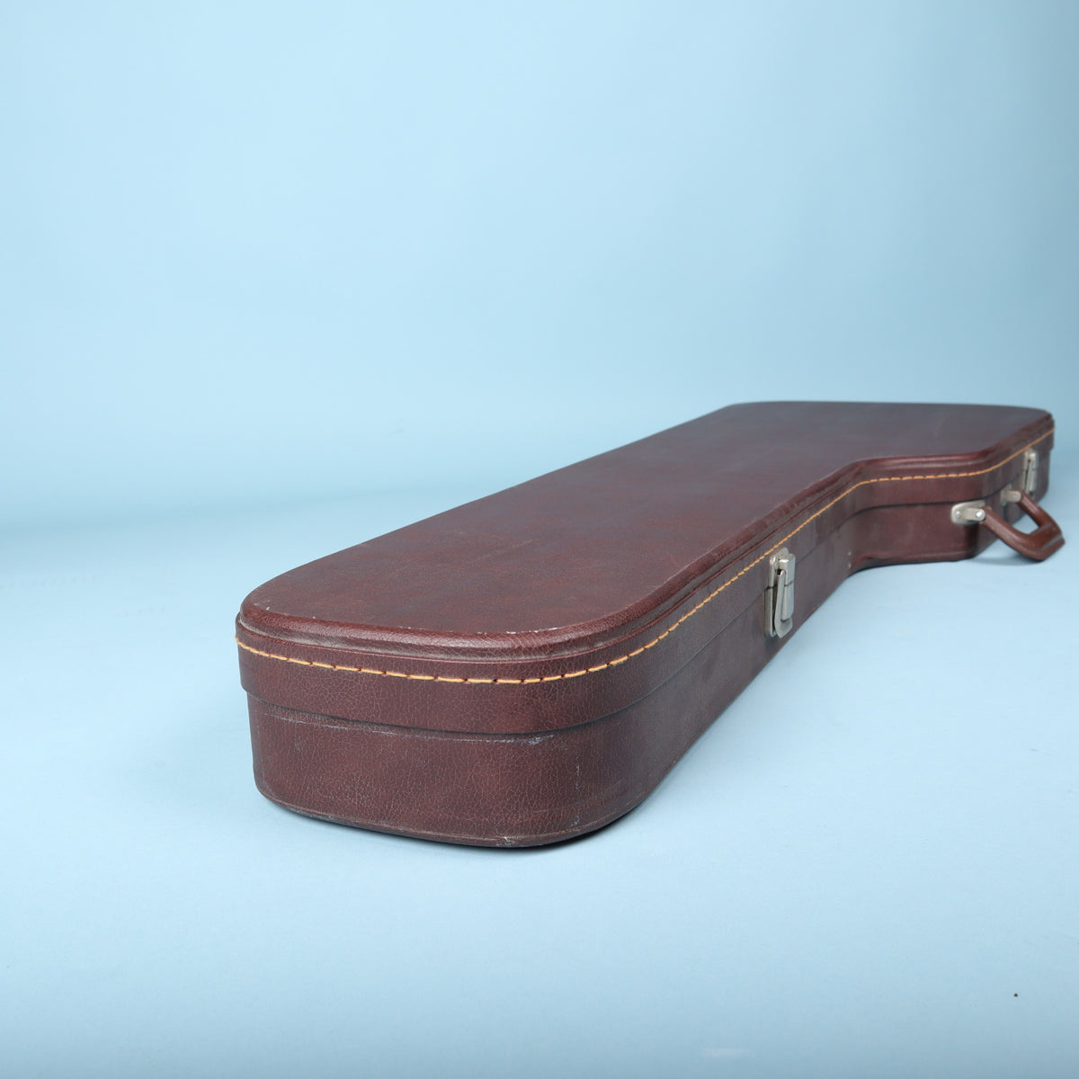 Bottom end view of the closed brown hardshell guitar case showing the protective piping.