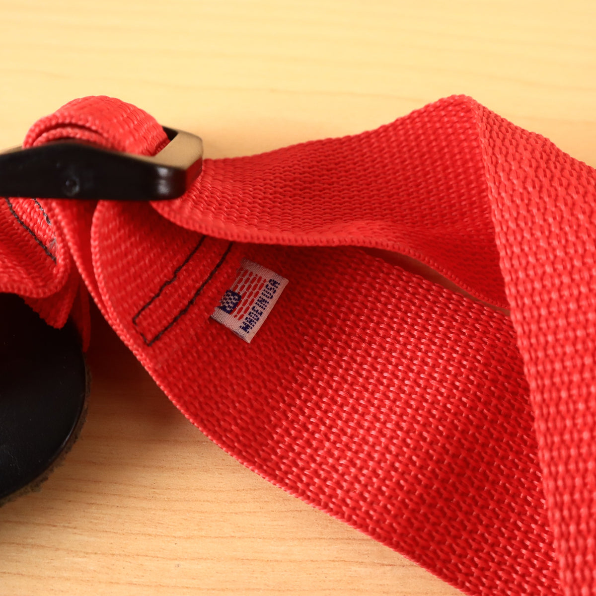 Close-up of sewn-in Made in USA tag and plastic adjustment buckle on red GHS strap.