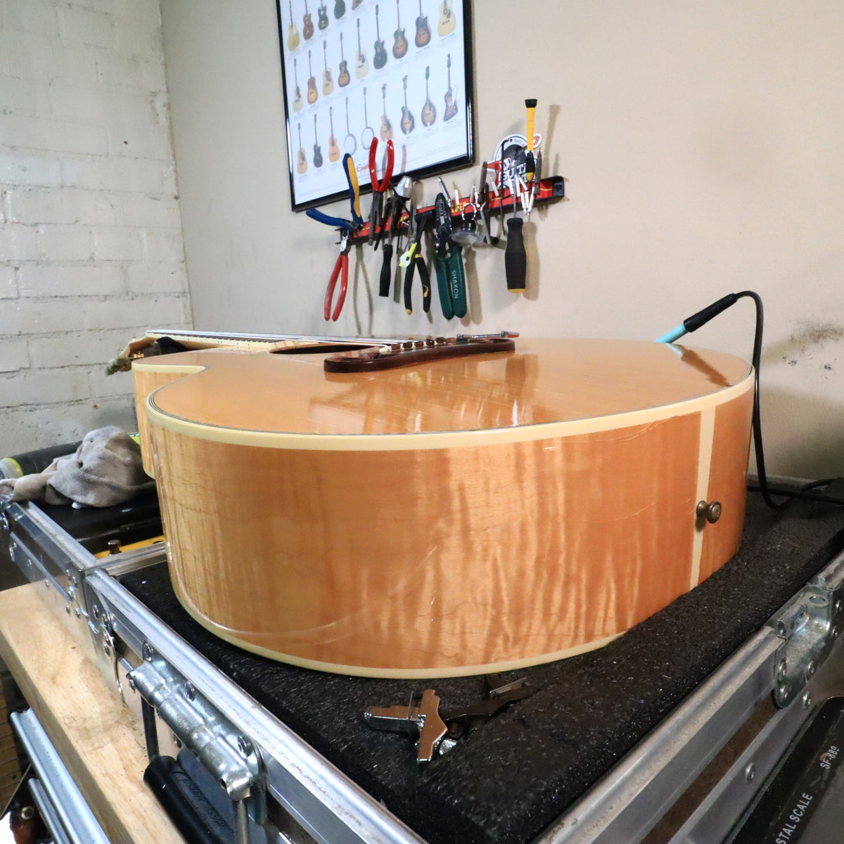 Side view of flame maple body resting on workbench.