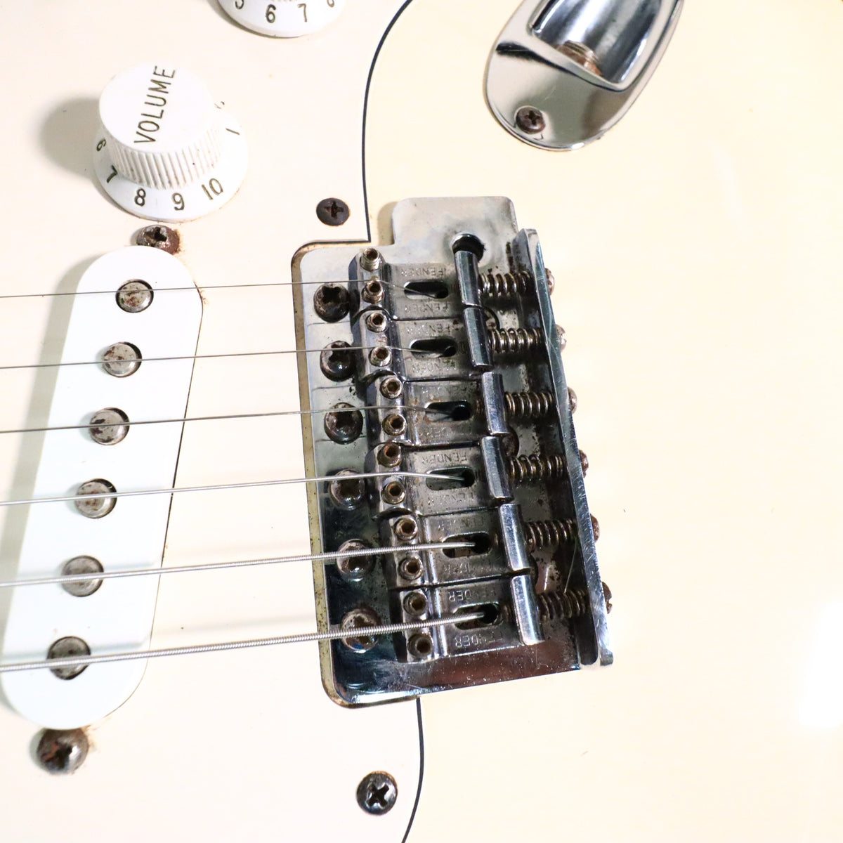 Close-up of Fender stamped tremolo bridge saddles and bridge pickup