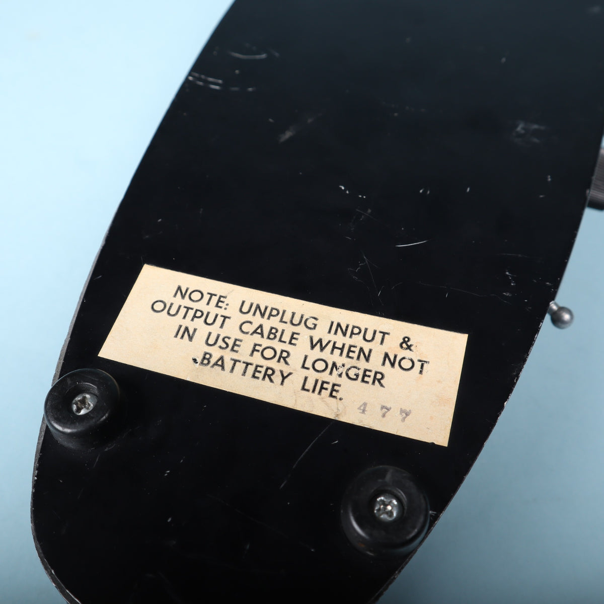 Close-up of the bottom baseplate sticker with battery caution text and inspection mark