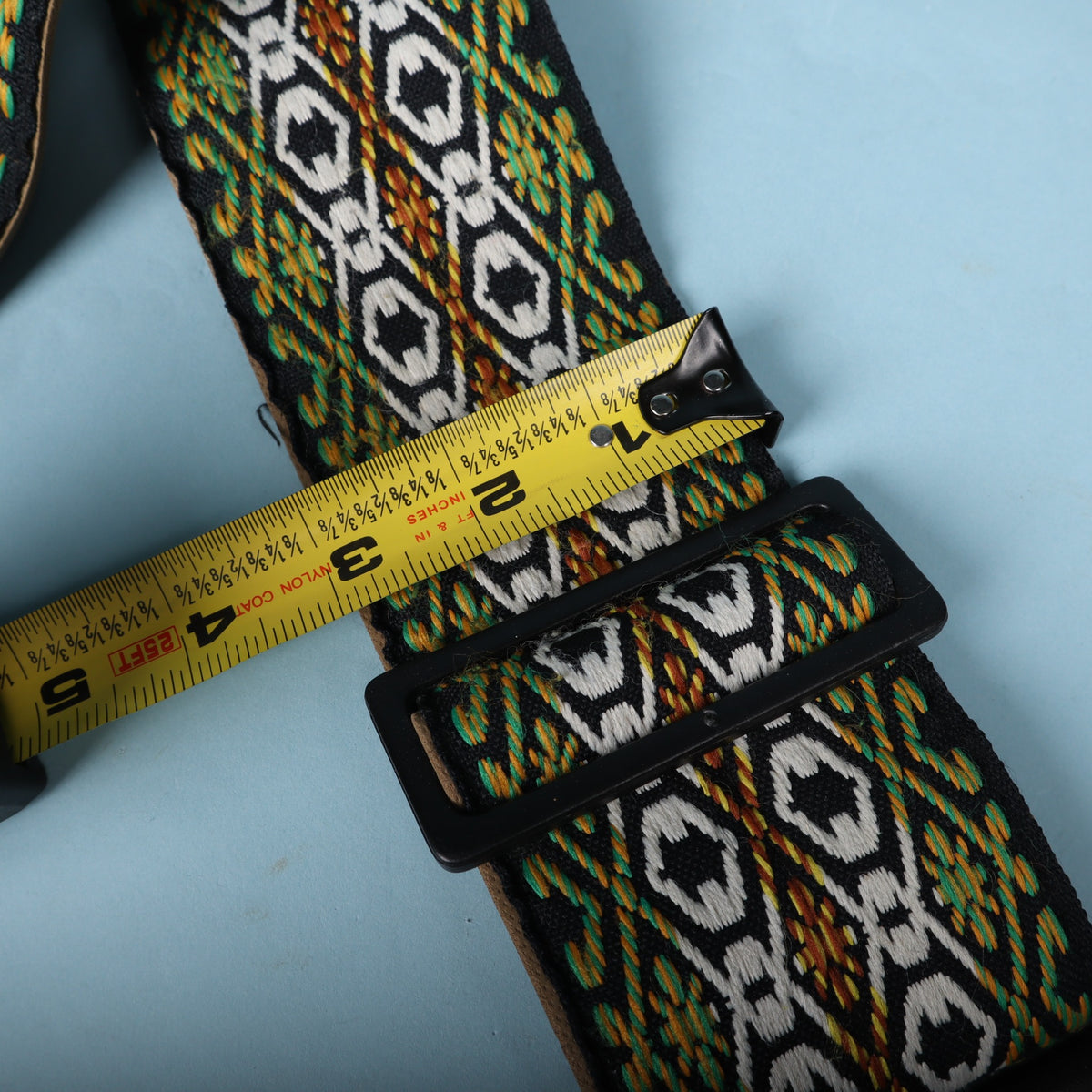 Measuring tape placed over the strap showing the woven ribbon width of 2 inches.