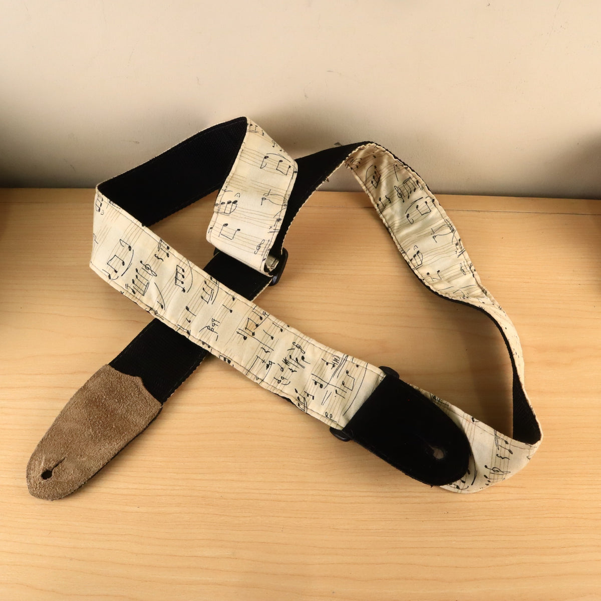 Guitar strap showing black webbing backing and tan suede leather end.