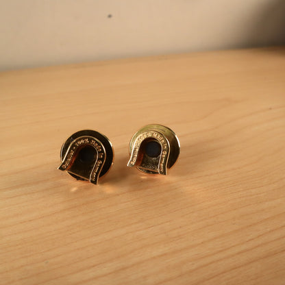 Overhead perspective of the two gold Schaller strap lock mechanisms on a light wood tabletop.