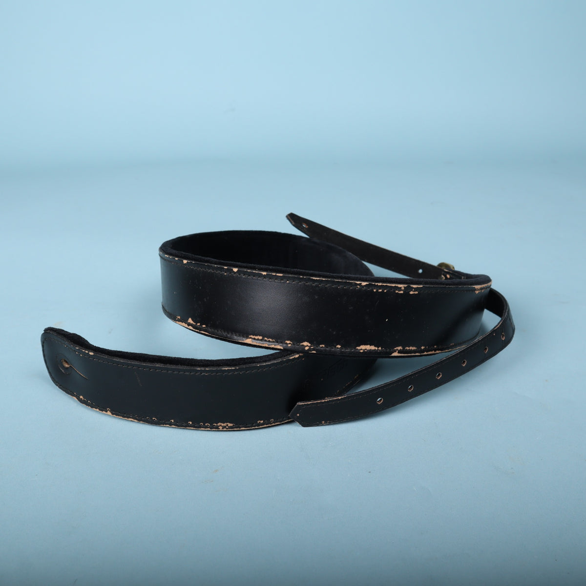 Gretsch black leather guitar strap coiled showing back lining.