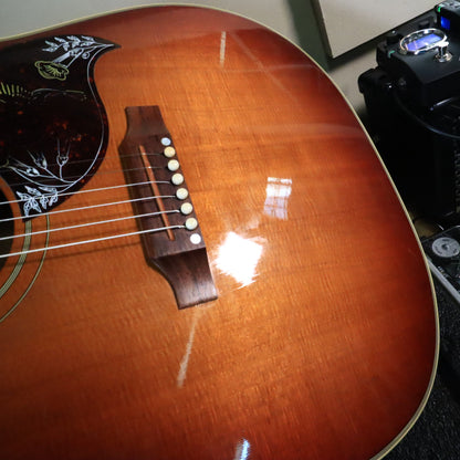 Close-up of the rosewood bridge, white bridge pins, and cherry sunburst finish on the guitar top.