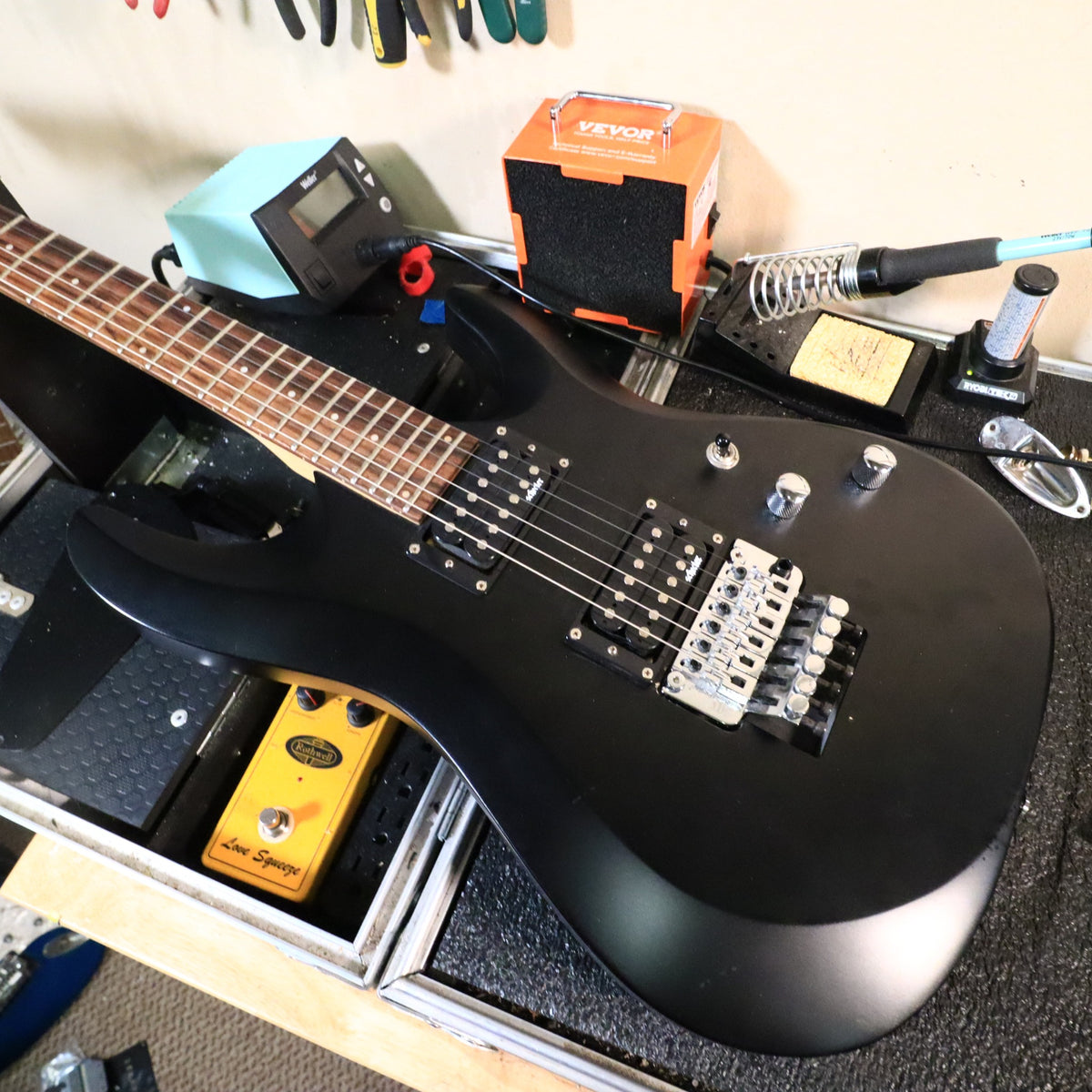 Schecter C-6 Deluxe FR resting on a workbench in a workshop setting.