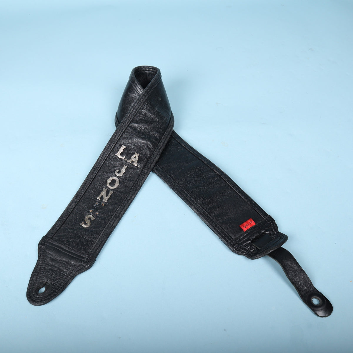 The Action padded leather strap folded to show the silver L.A. JONES lettering on the main face.
