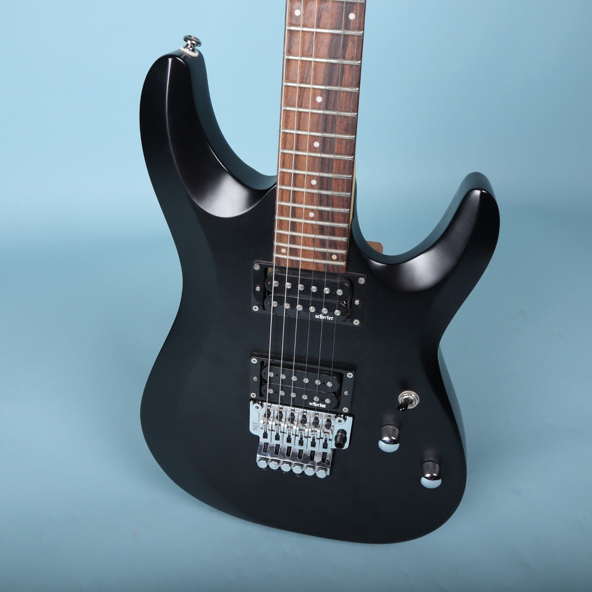 Angled front view of the Schecter C-6 Deluxe FR guitar body showing controls and bridge.