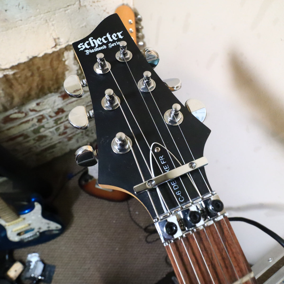 Close-up of the headstock face, locking nut, and truss rod cover on workbench.