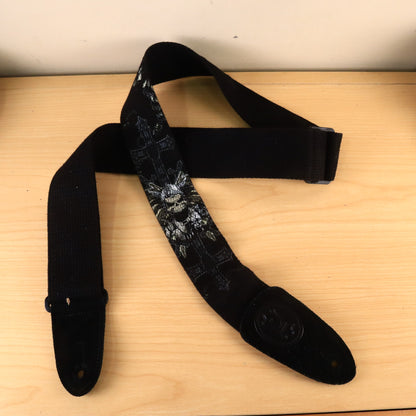 Overview of black Levy's guitar strap with printed skull design laid on a wooden surface.