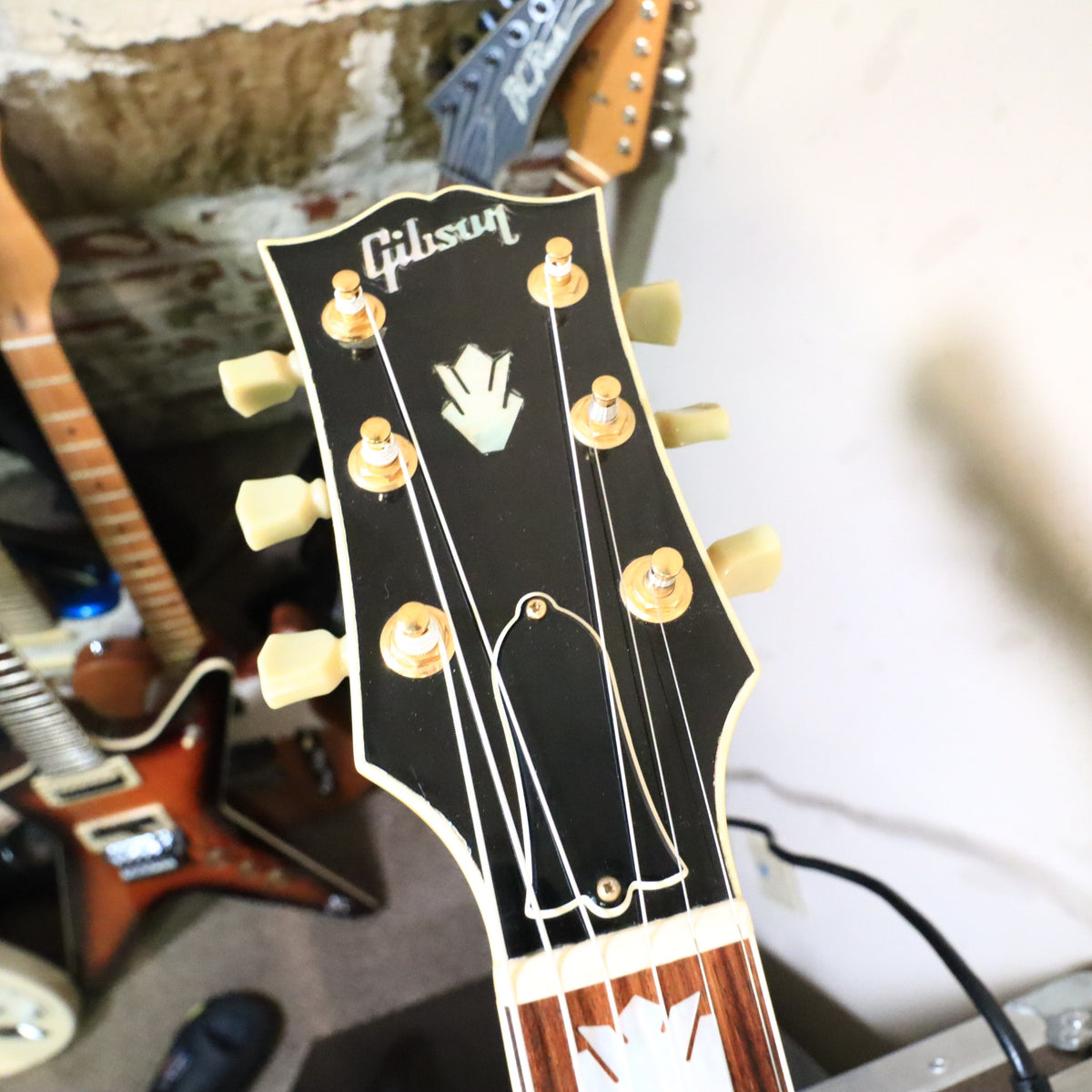 Headstock close-up showing gold tuner posts and truss rod cover.